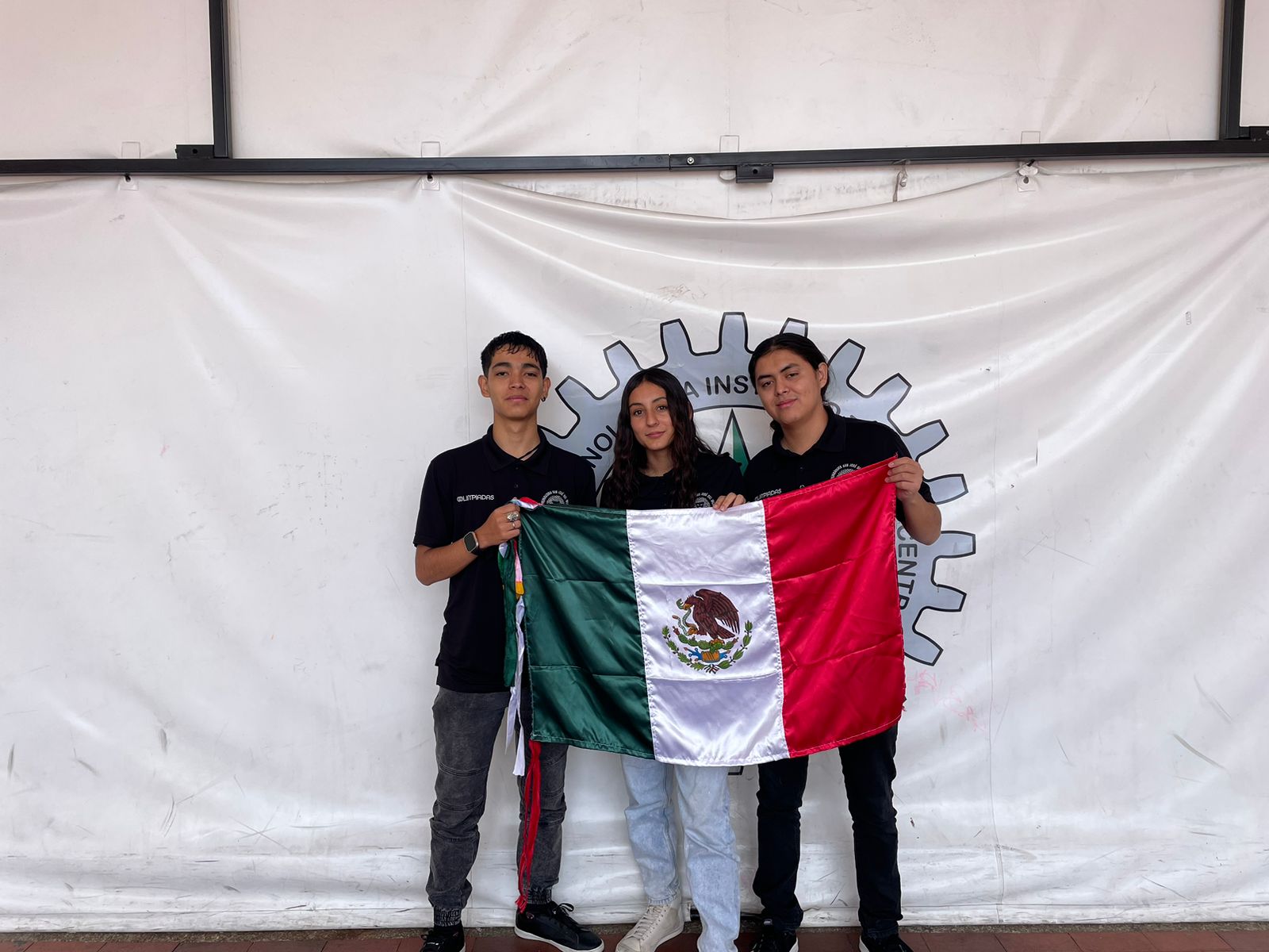 Integrantes de equipo participante en Infomatrix Colombia sostienen bandera de México