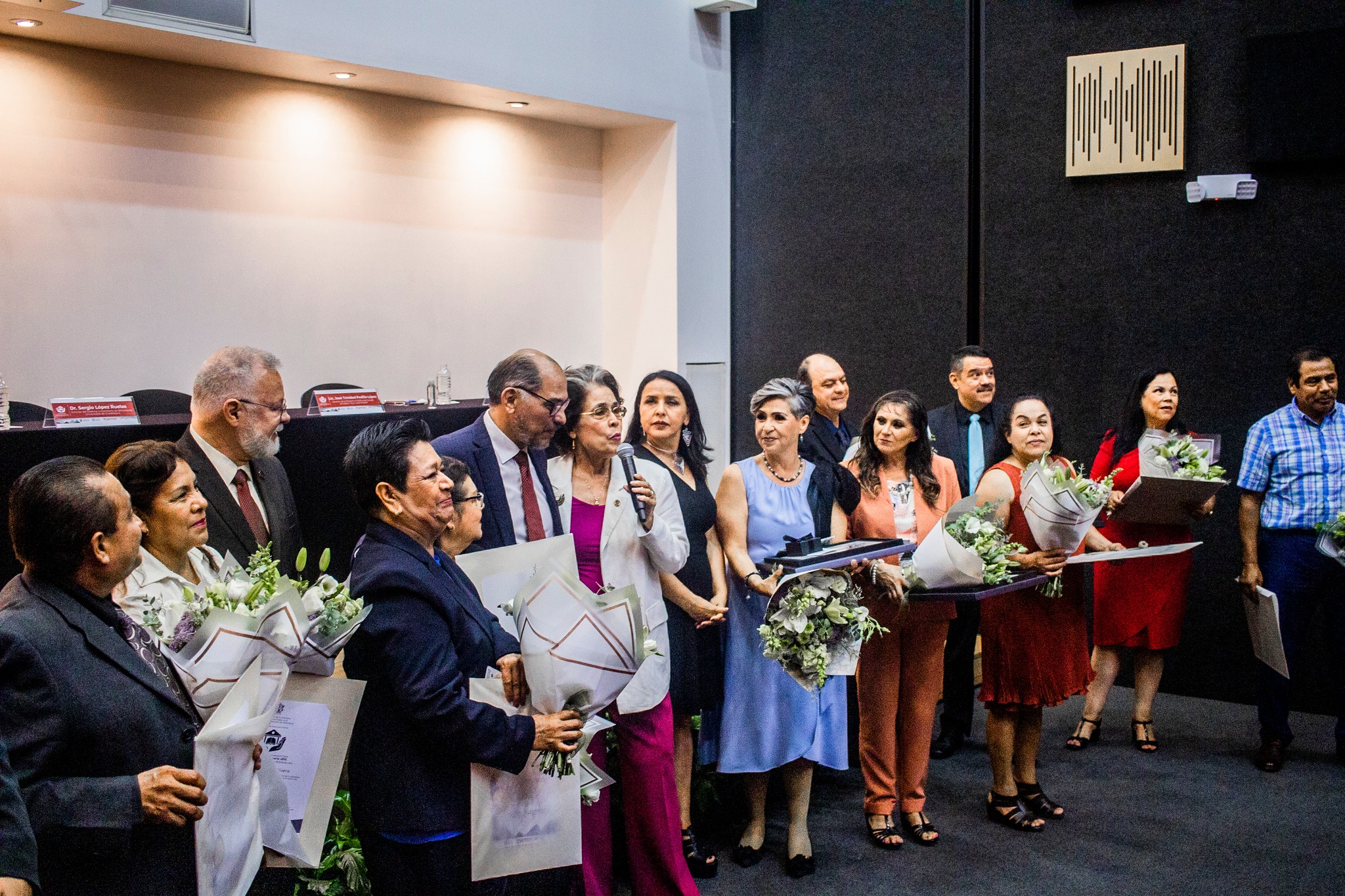 Bibliotecarios reconocidos junto a autoridades del evento en auditorio frente a asistentes