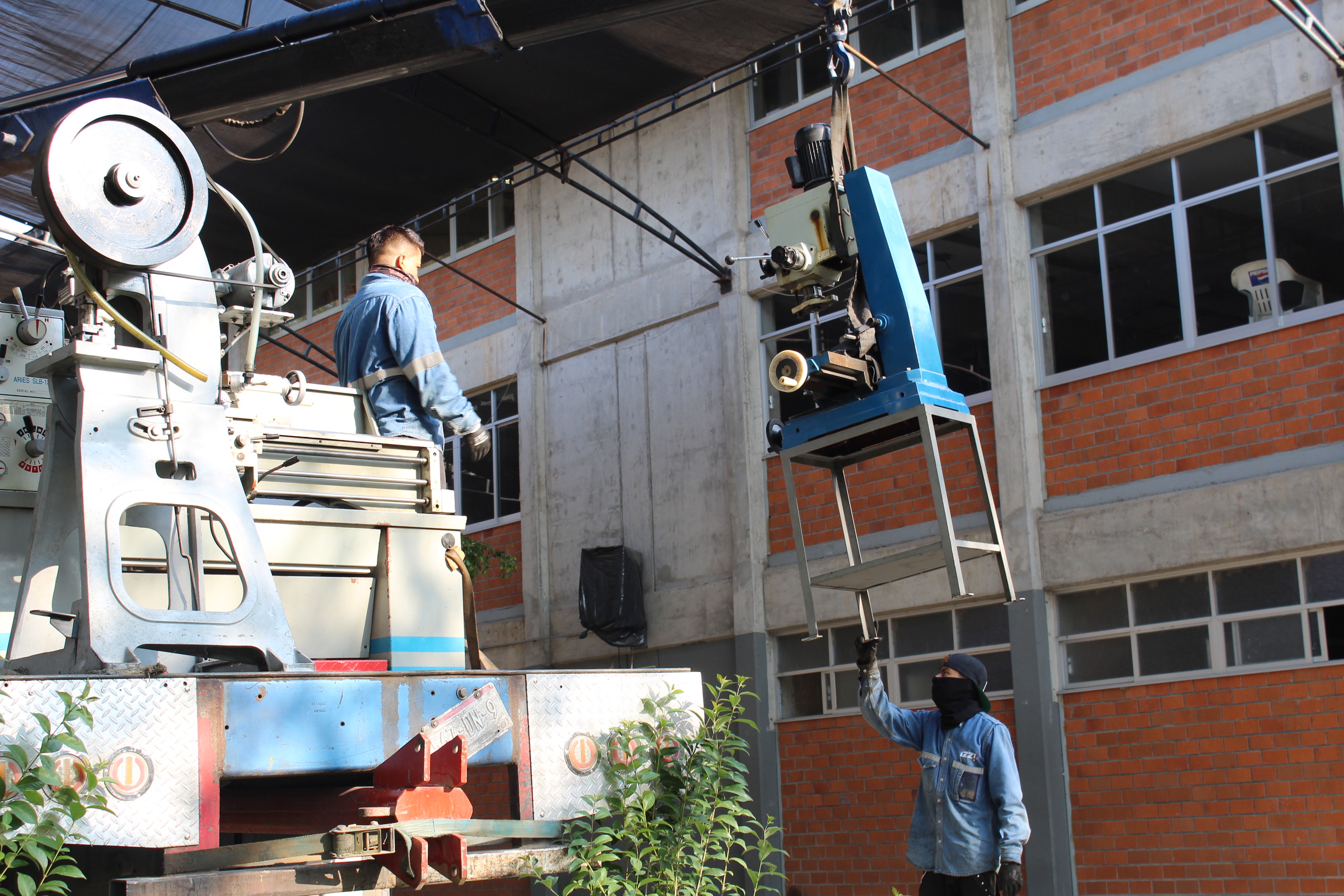 Trabajadores realizan mudanza de maquinas de taller