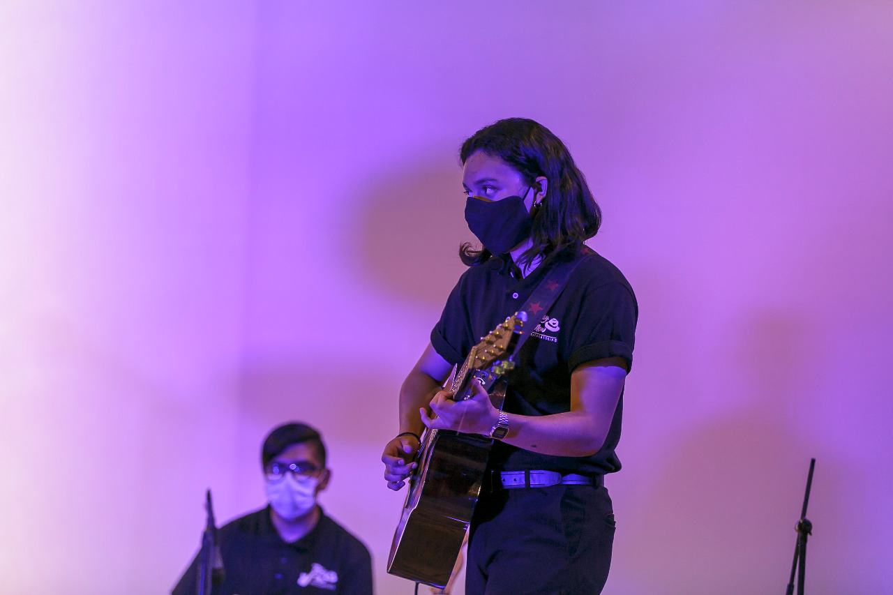 Alumnos con instrumentos musicales en escenario