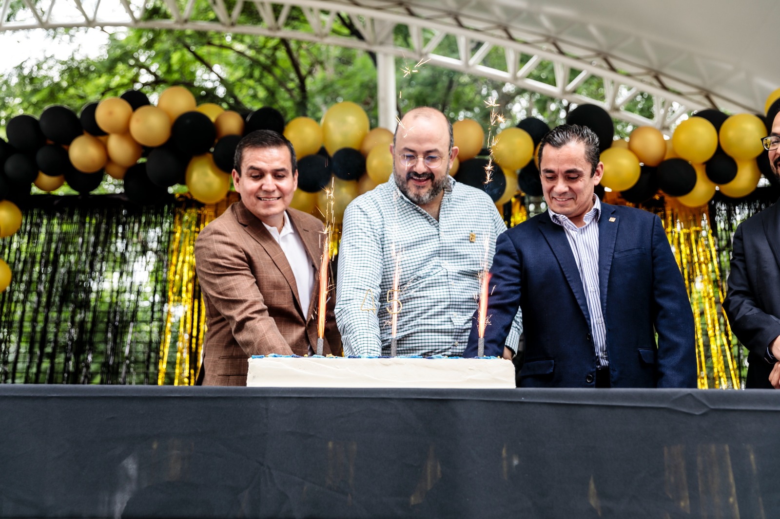 Autoridades del evento en escenario parten pastel