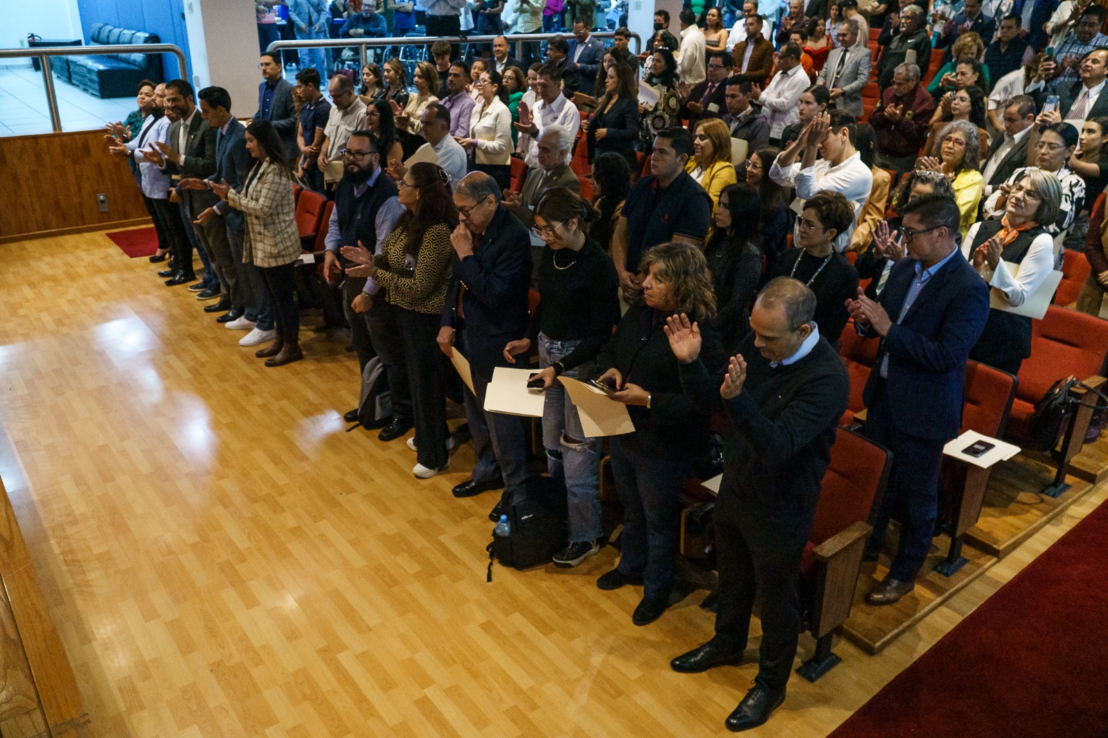 asistentes de pie en auditorio