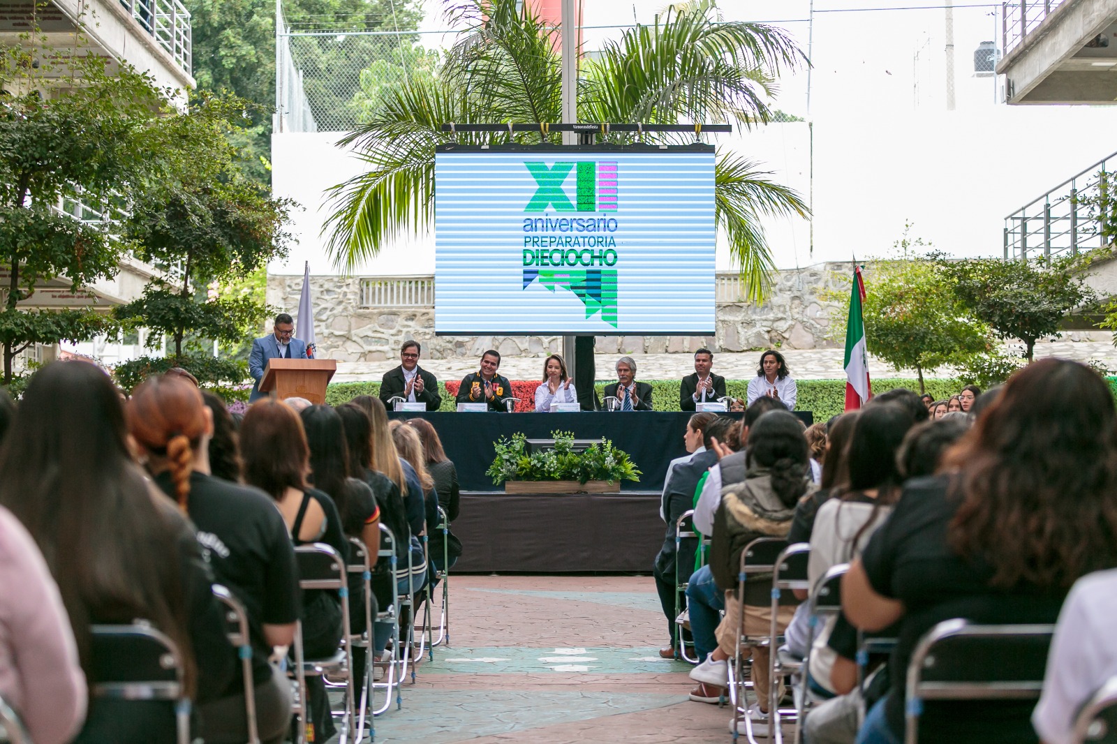 Autoridades del evento sentados en presidium frente a asistentes al evento sentados