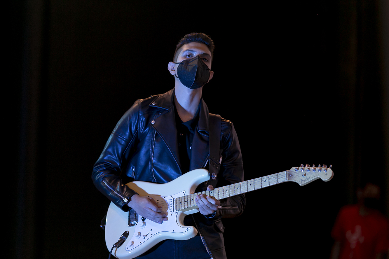 Joven toca guitarra en el escenario