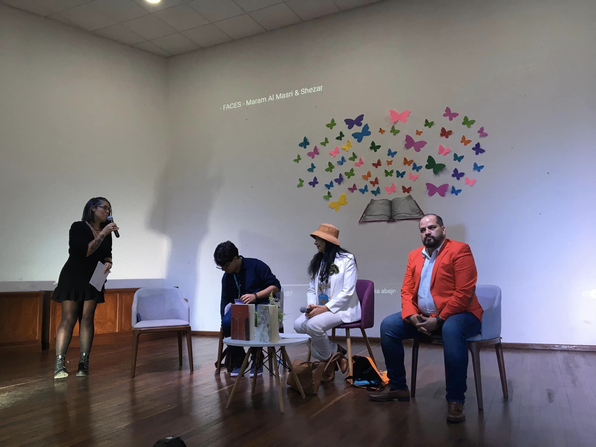 Escritora y autoridades del evento frente a estudiantes en charla