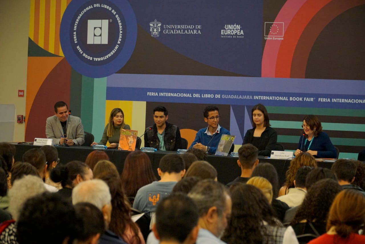 alumnos en presidium que participan en la edición de la revista frente a asistentes en auditorio