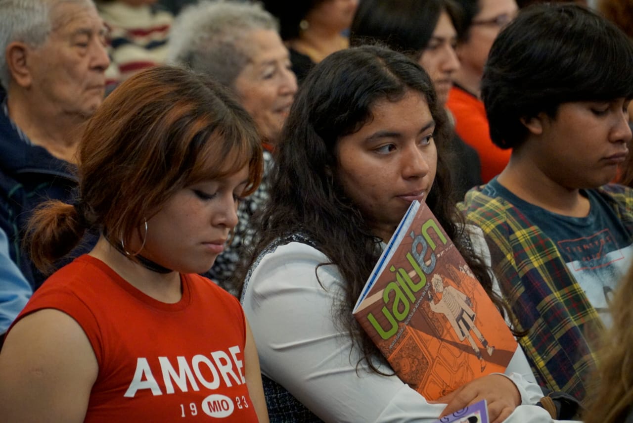 alumnos en presidium que participan en la edición de la revista frente a asistentes en auditorio