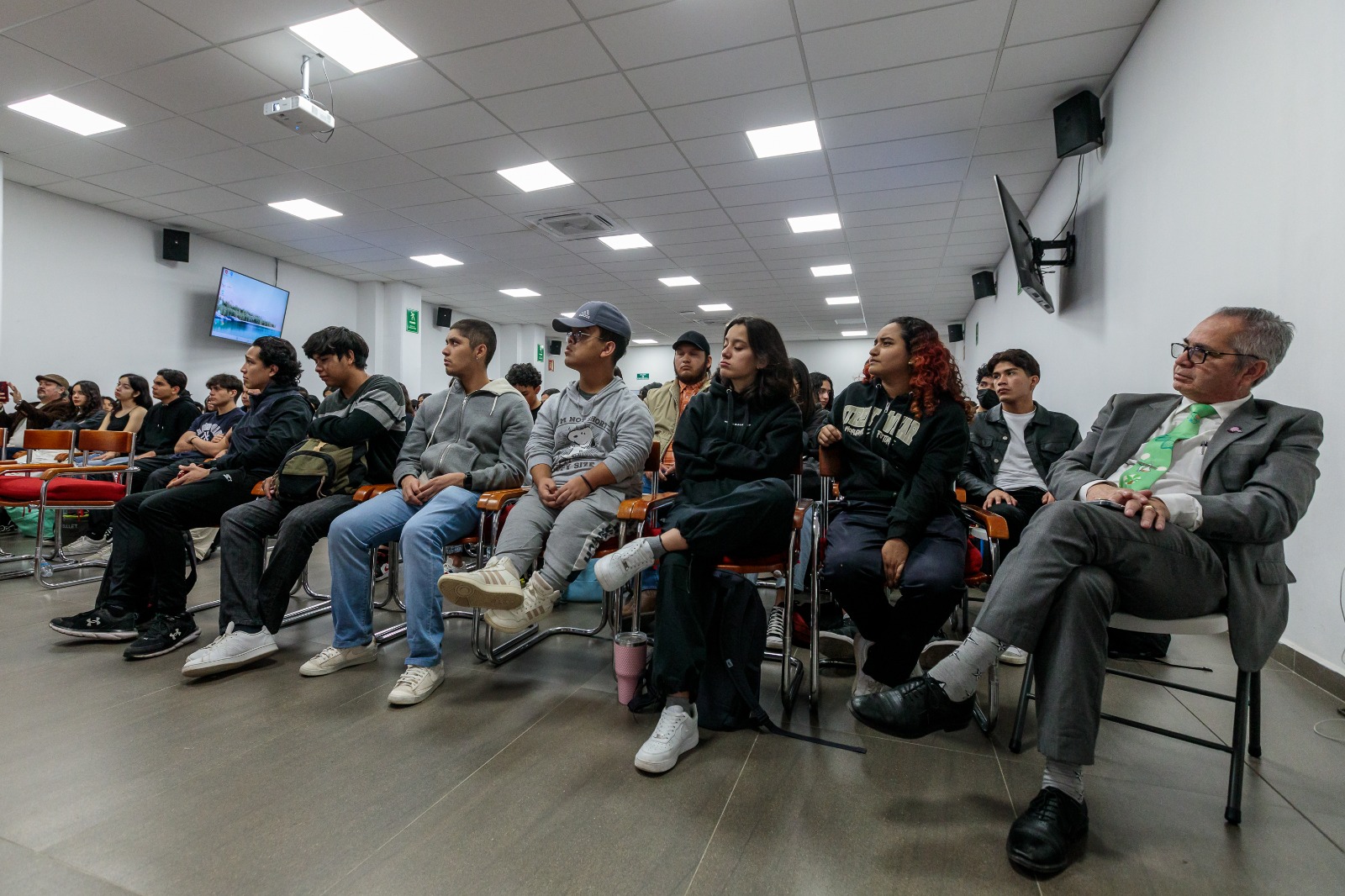 Asistentes al evento sentados usan su celular
