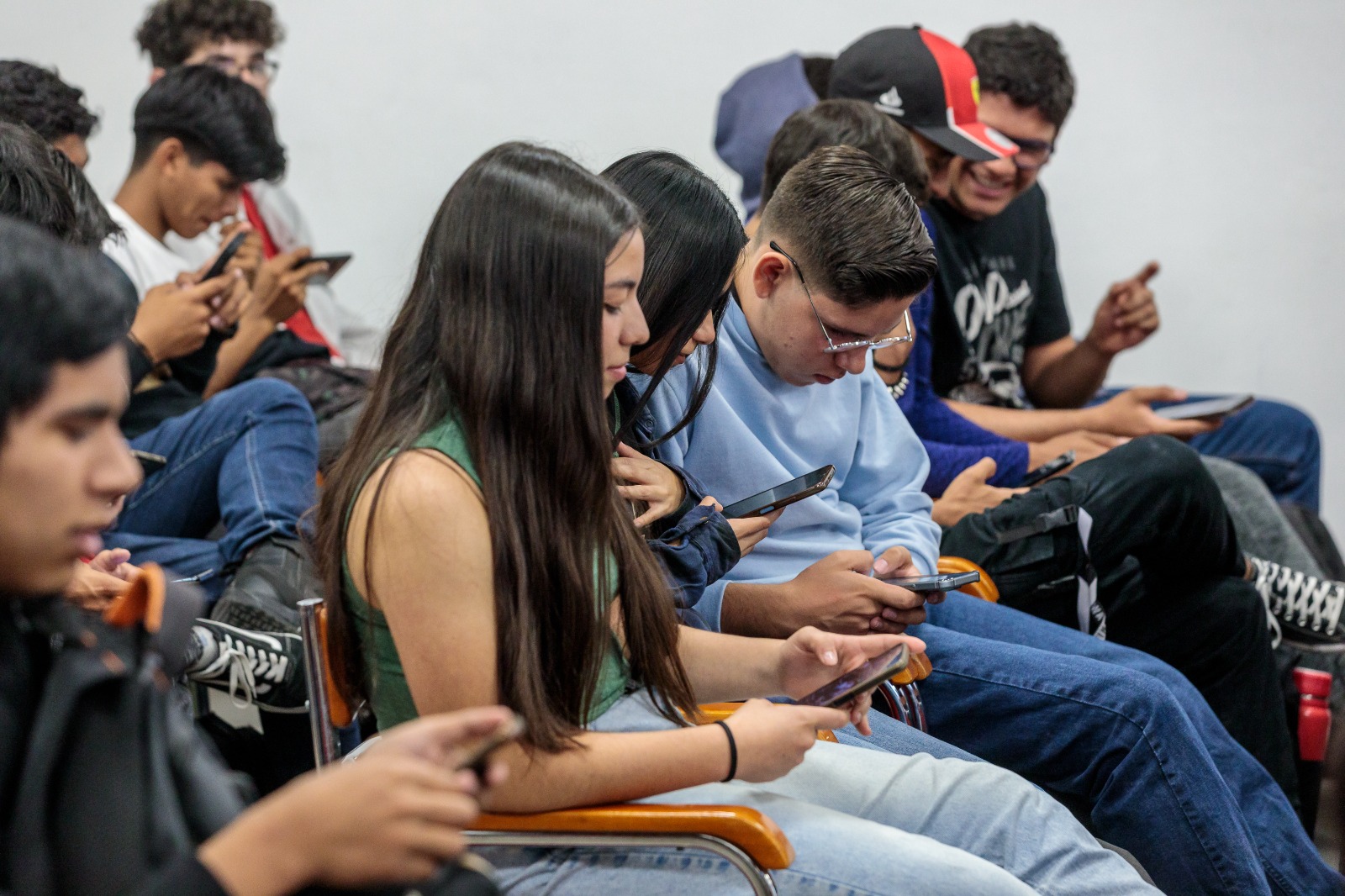 Asistentes al evento sentados usan su celular
