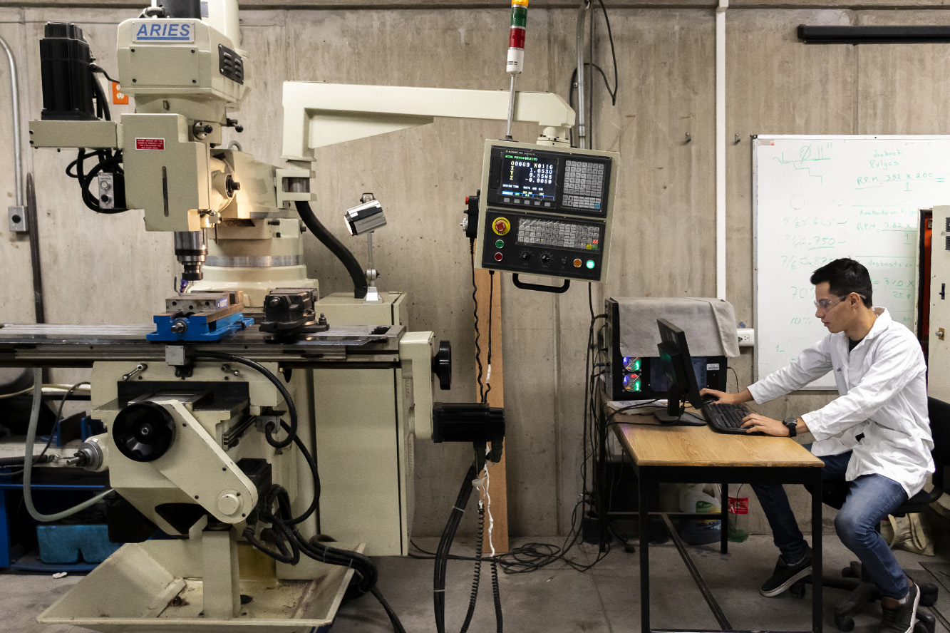 Joven manipula máquina en taller