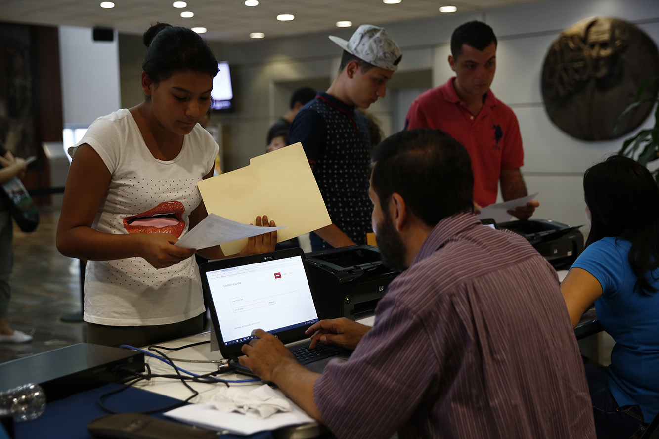 Persona usa computadora y apoya a mujer para realizar un trámite