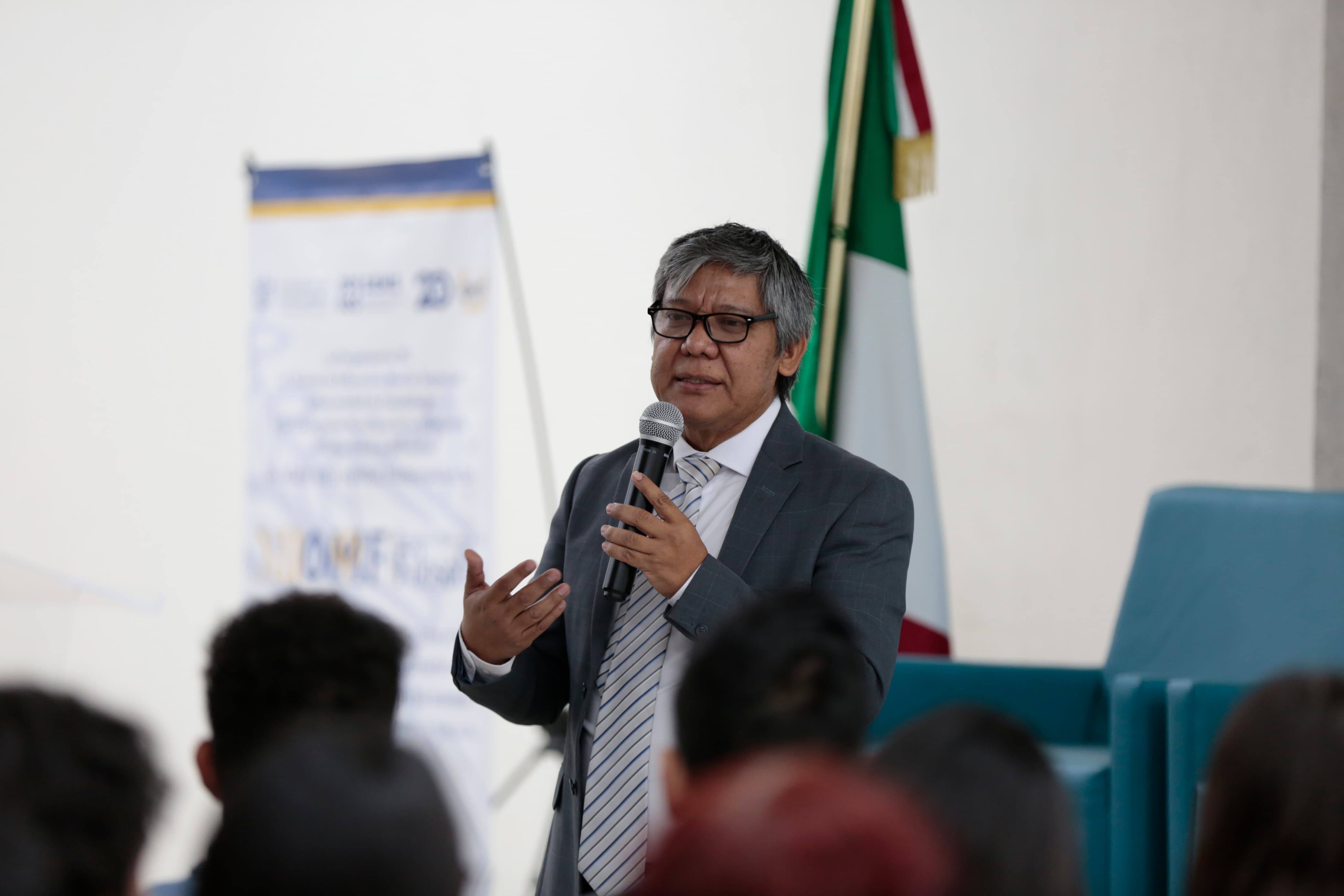 Autoridades del evento de pie en presidium frente a asistentes al evento sentados