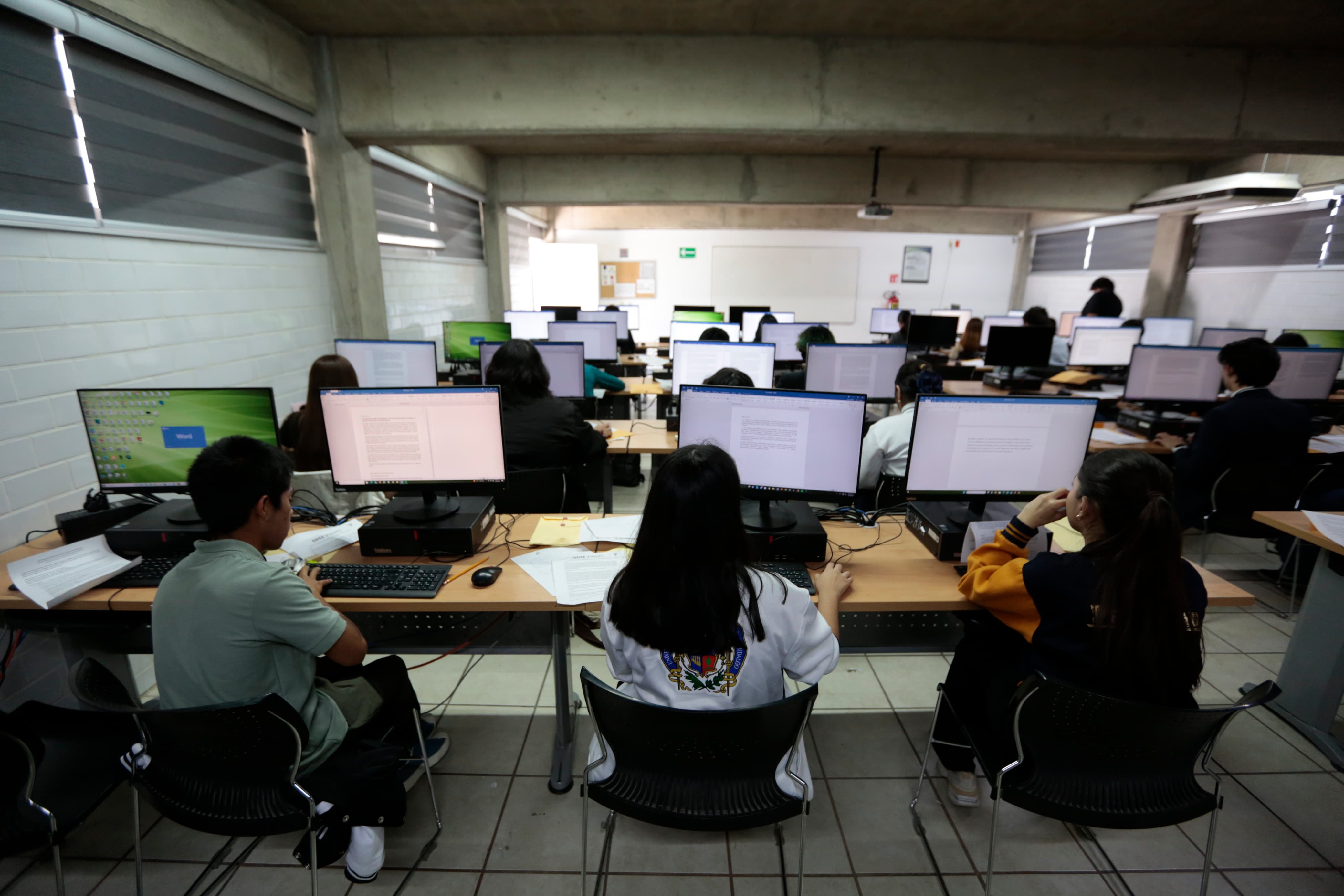 Participantes del evento sentados de espaldas usando computadora