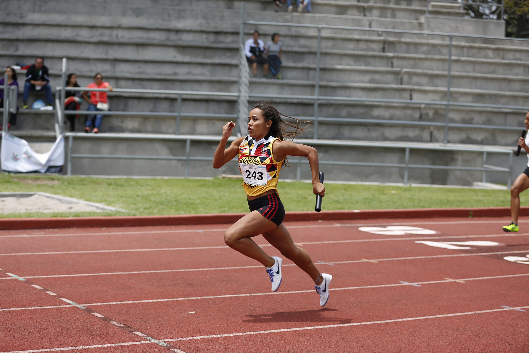 Atleta con estafeta corriendo en pista de atletismo