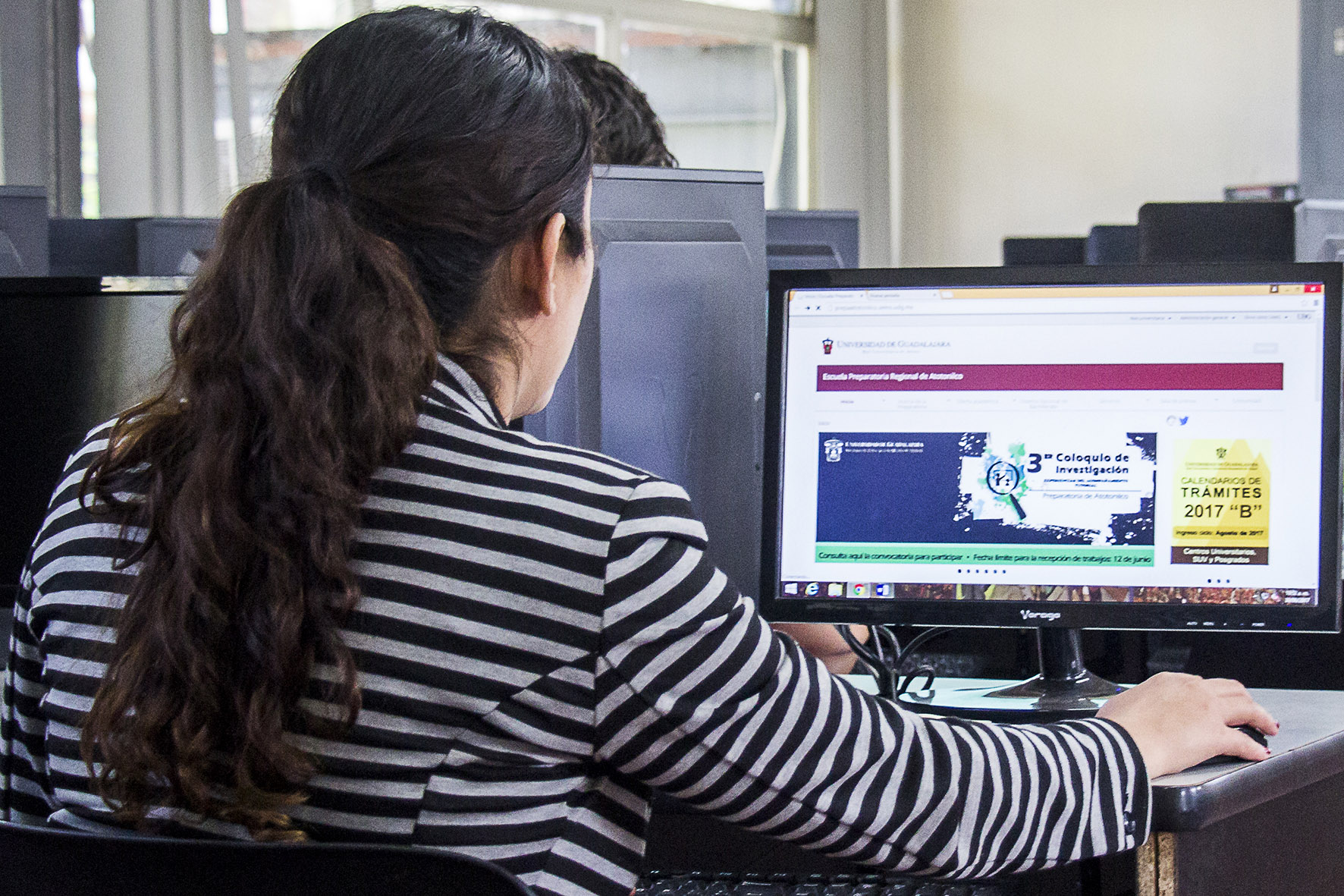 Docente en computadora en aula de cómputo