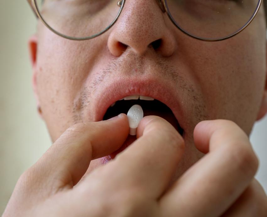 Hombre llevando medicamento a la boca