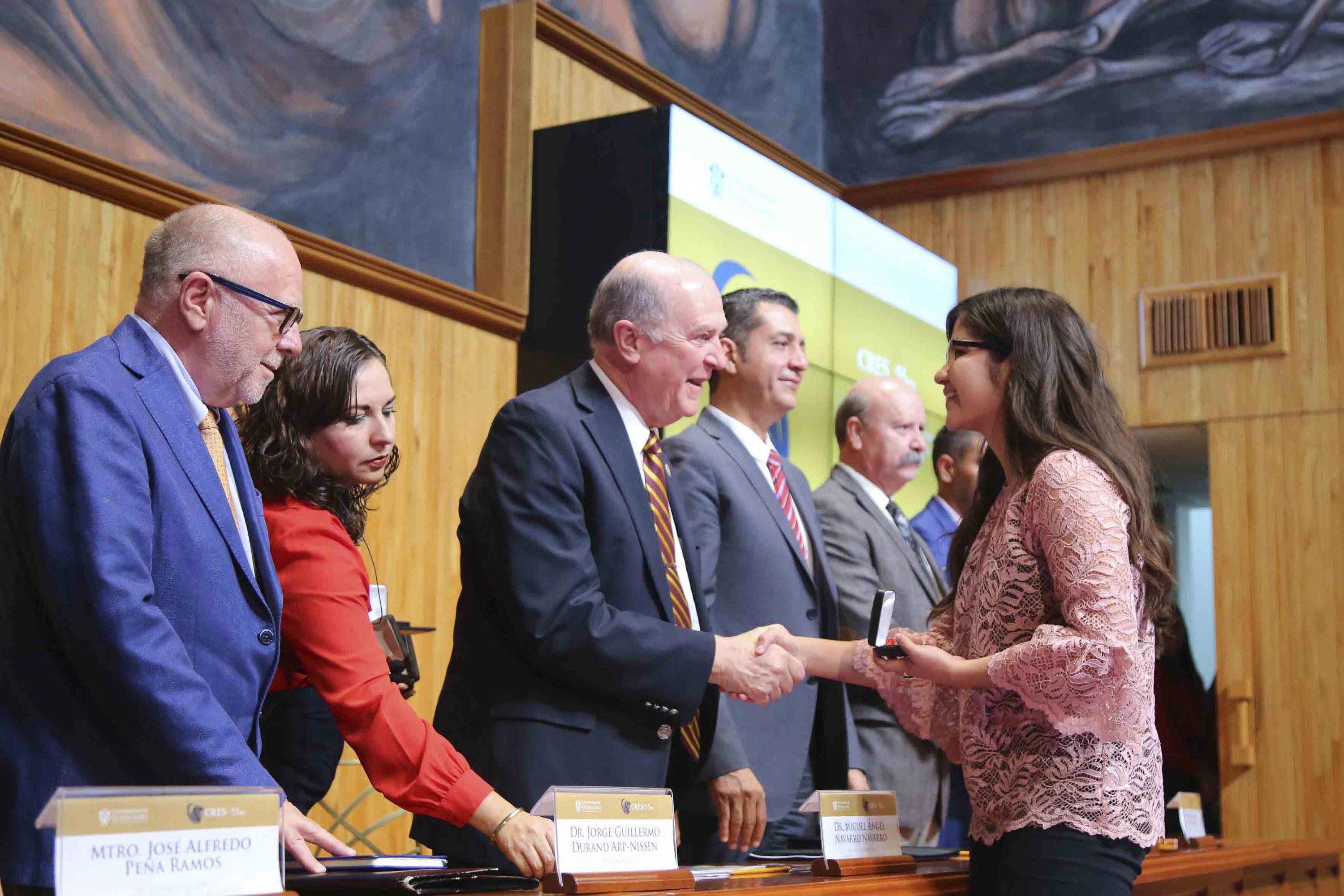 Integrantes de la mesa del presídium entrega medalla alumna
