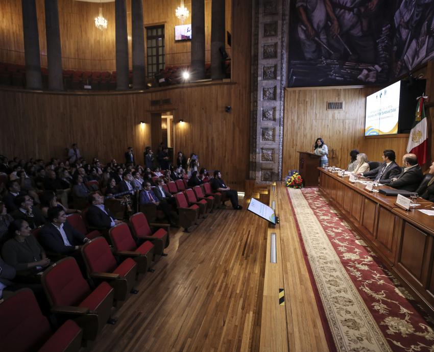 Autoridades del evento en presidium frente a asistentes en auditorio