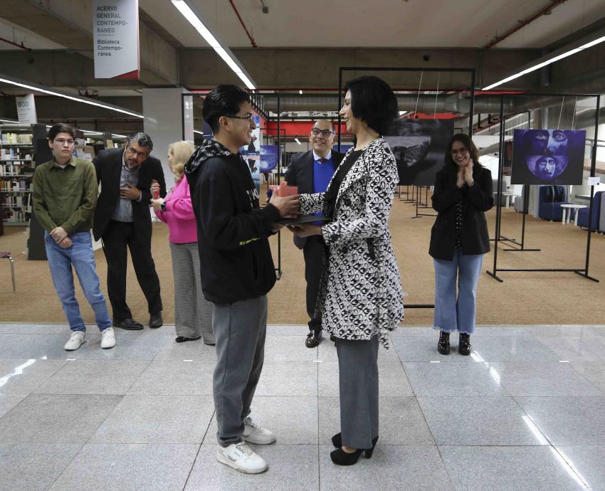Joven de pie recibe premio de mujer