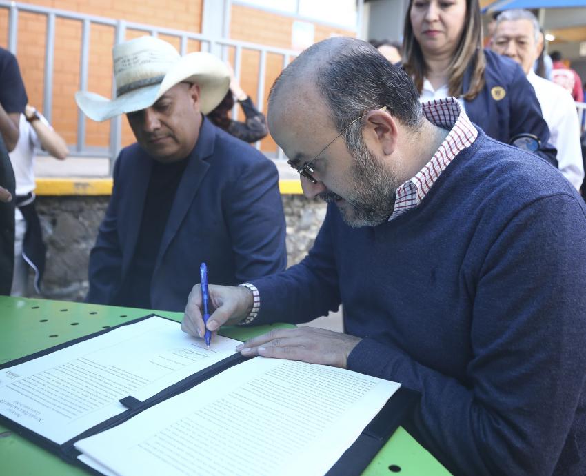 doctor Ricardo Villanueva Lomelí sentado firma documento