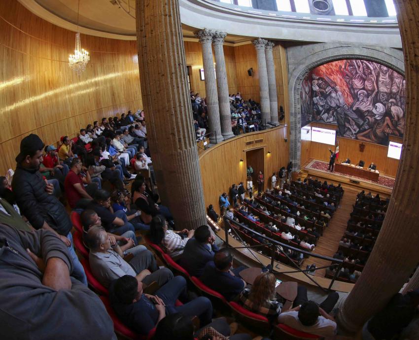 consejeros universitarios sentados en auditorio emitiendo su voto