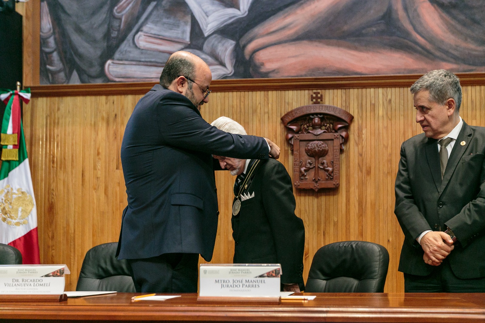 doctor Ricardo Villanueva Lomelí coloca en el cuello del maestro José Manuel Jurado Parres medalla