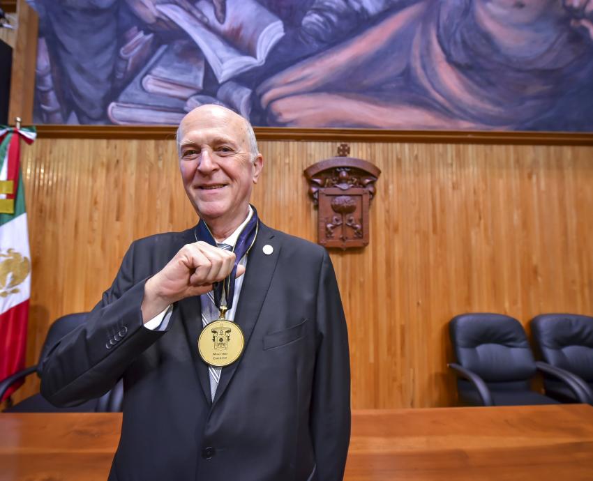 homenajeado sostiene medalla de reconocimiento