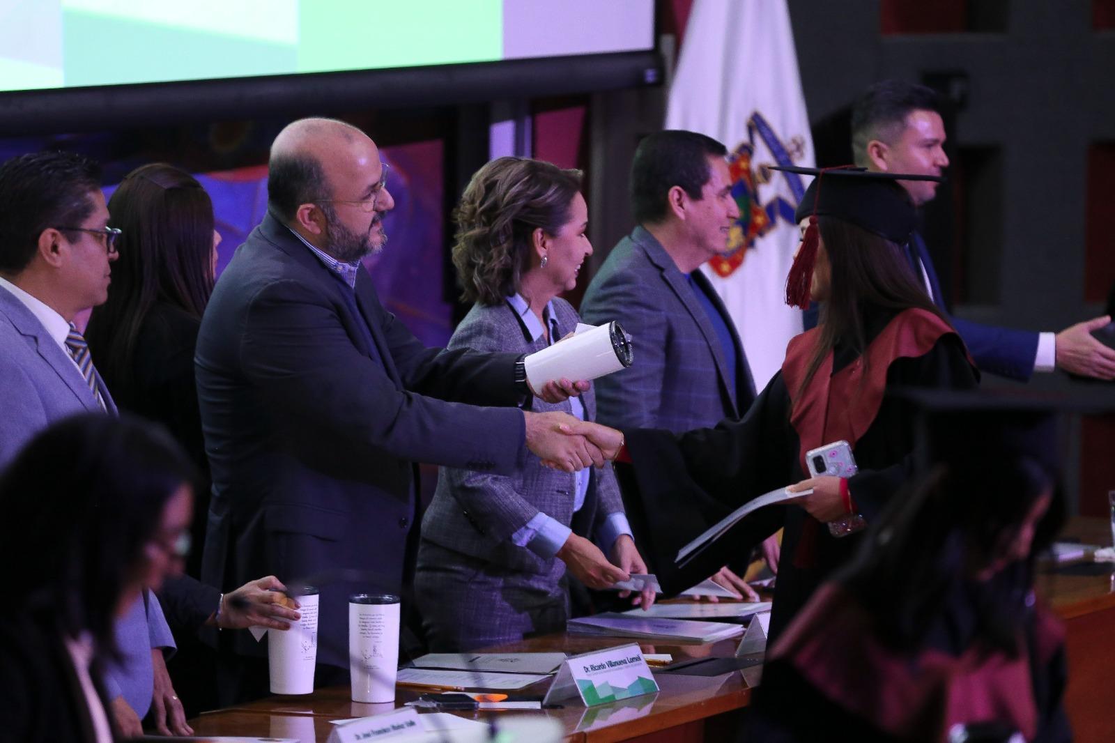 Autoridades del presídium entregando presente a graduados