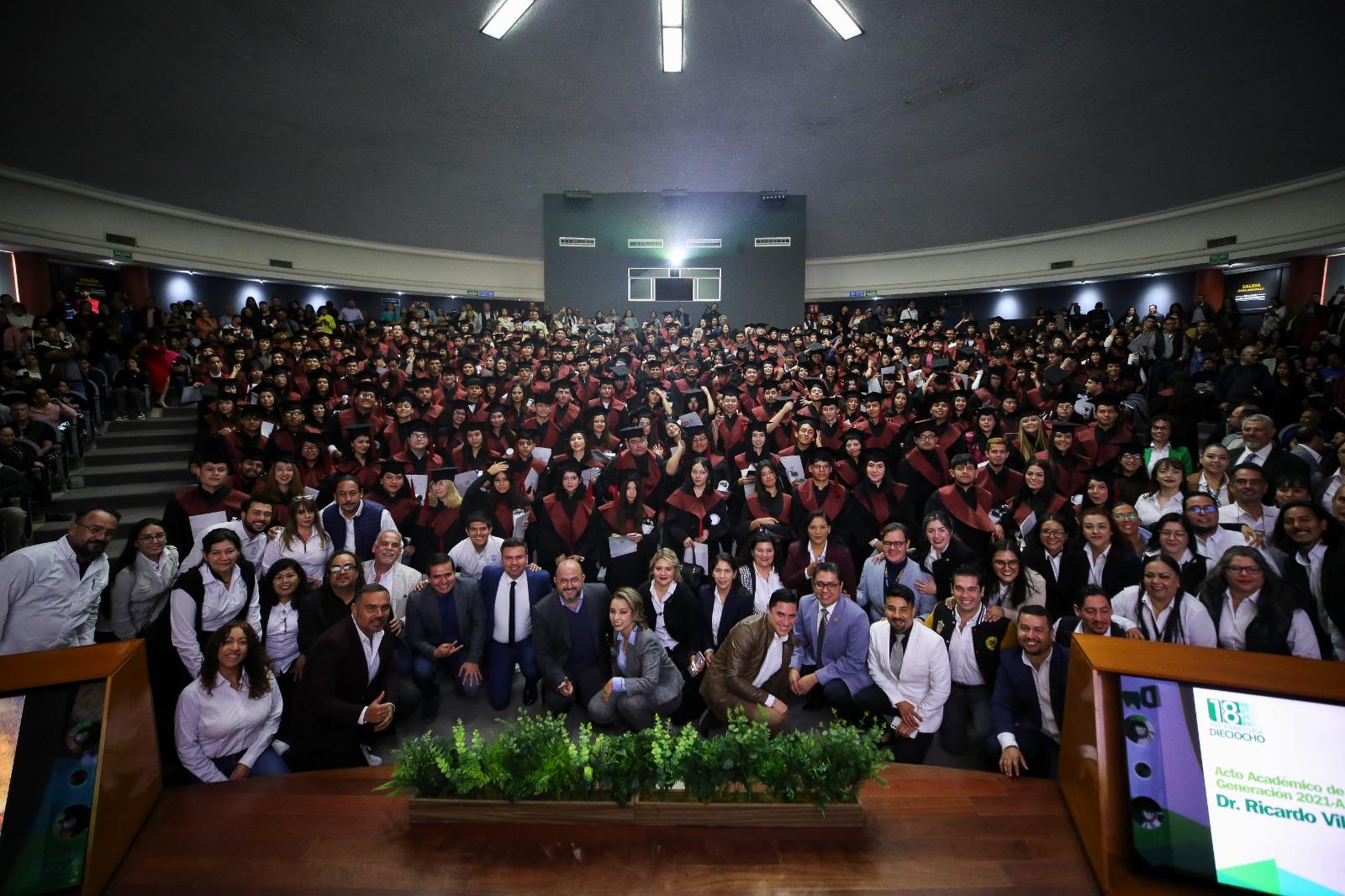 Autoridades del evento junto a todos los graduados en auditorio