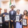 Bibliotecarios reconocidos junto a autoridades del evento en auditorio frente a asistentes