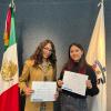 Dos mujeres de pie junto a bandera de México y U D G sostienen reconocimientos