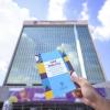 Mano sostiene guía impresa frente edificio de la Universidad de Guadalajara